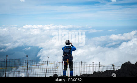 Climber looking over the clouds from the summit of Mount Fuji in Japan Stock Photo