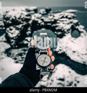 Holding and using a compass for hiking in a snowy winter landscape Stock Photo