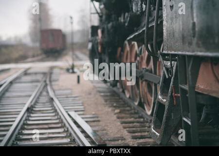 Steel stairs in Vintage steam train on wet rails of the railway station on a cloudy day with rain Stock Photo