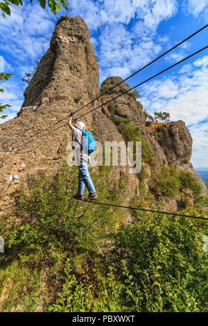 Climber on the suspension bridge in Deanna Orlandini via ferrata, Rocche del Reopasso, Liguria, Italy Stock Photo