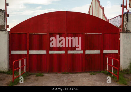 Main entrance of a small football stadium, big red metal doors and gates details. Stock Photo