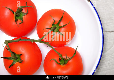 ripe red vine grown organic tomatoes in white metal bowl Stock Photo