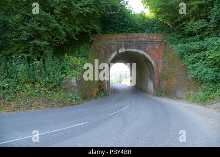 Railway bridge: a disused brick-built railway bridge allows a road to pass beneath it Stock Photo