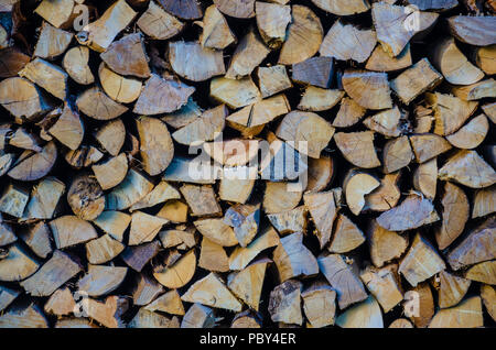 A pile of chopped logs ready to use as fuel in a wood burning stove. Stock Photo