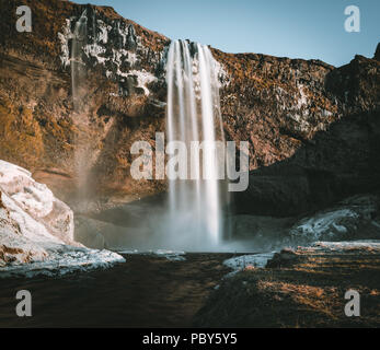 Wonderful landscape from Seljalandsfoss Waterfall in Iceland on a clear day with blue sky and snow. Stock Photo