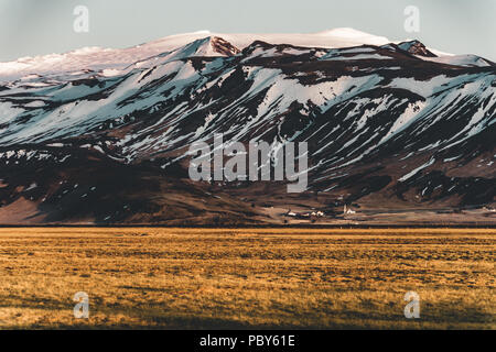 Iceland typical mountain winter scene with grass in foreground and massive mountain in background. Stock Photo