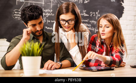 Young professional team of startuppers working with tablet and papers in the office on the some diagrams background Stock Photo