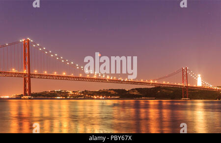 View of the lunar eclipse, the longest blood moon of the 21st century, over the 25th April Bridge in Lisbon, Portugal Stock Photo