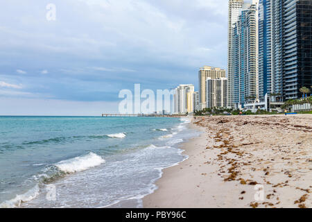 Sunny Isles Beach, USA - May 7, 2018: Apartment condo hotel buildings during evening in Miami, Florida with skyscrapers urban sand exterior, pier, wav Stock Photo