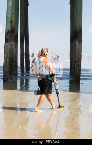 Old Orchard Beach, USA - 1st September 2014: Man walks along the beach and under the pier at low tide, searching for lost money and jewelry with a met Stock Photo