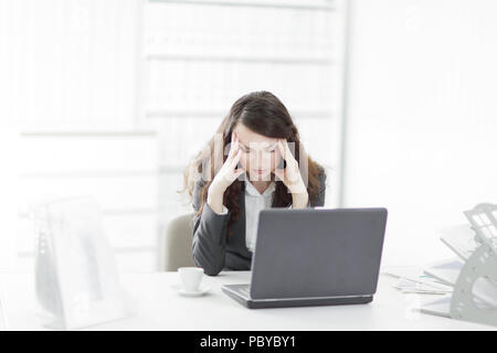 puzzled businesswoman sitting behind a Desk Stock Photo
