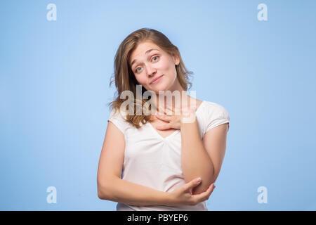 Pleased Caucasian woman wearing white top smiling broadly and keeping hand on her cheek, glad to receive compliments Stock Photo
