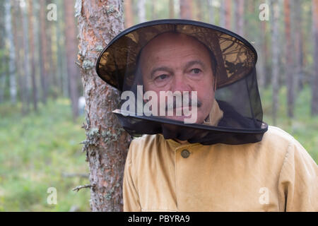 Mature caucasian man in special anti mosquito cap standing in forest and rest Stock Photo