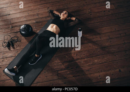 Top view of young woman relaxing on yoga mat after workout. fitness woman resting after exercising at gym. Stock Photo