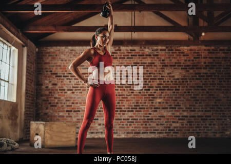 fitness woman doing exercising with kettle bell. Determined female model doing workout with kettle bell at gym. Stock Photo