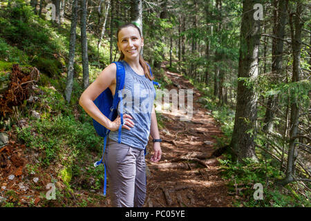 Young happy backpacker woman walking in woods Stock Photo
