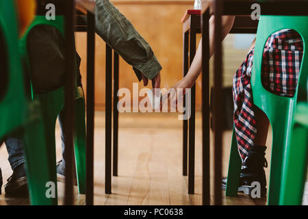 Two students hands passing notes to each other secretly during class. Young students cheating on an exam. Stock Photo
