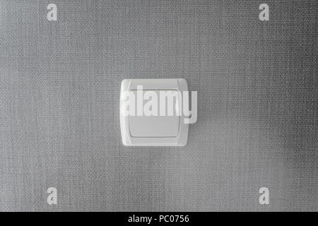 Light switch. Plastic mechanical switch of white color installed on a light gray wall. Stock Photo