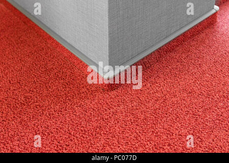 Carpet floor with a carpet baseboard on a grey wall. Stock Photo