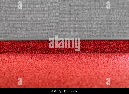 Carpet floor with a carpet baseboard on a grey wall. Stock Photo