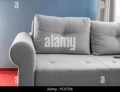 Comfortable grey couch in a living room with blue wall and red floor. Stock Photo
