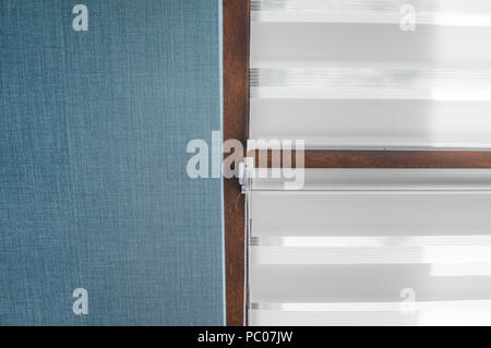 White fabric roller blinds on the plastic window with wood texture in the living room with blue wall Stock Photo