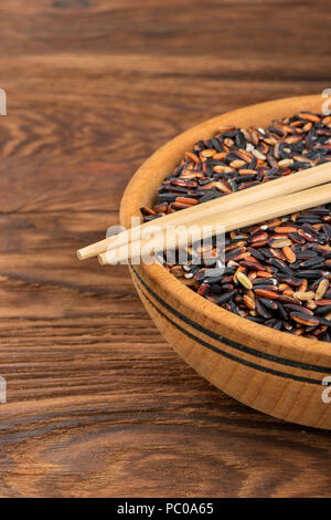 Black rice in a bowl with chopsticks on the table closeup Stock Photo
