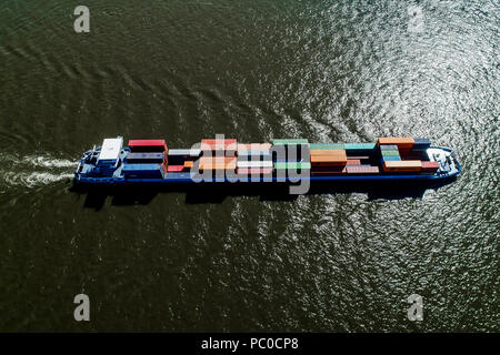 Rhine - Netherlands, July 14, 2018: aerial view of a merchant ship with a container crossing the river Rhine in a region of the Netherlands