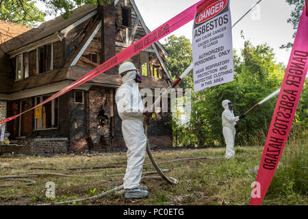Detroit, Michigan - Using protective clothing to guard against asbestos exposure, workers demolish abandoned houses. They spray water on the buildings Stock Photo