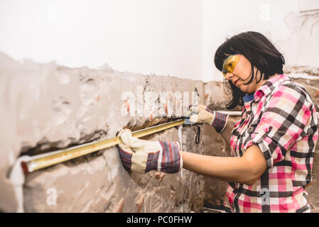 Clever woman repairing her bathroom sink pipe with  positive attitude. Using measuring tape ruler. Stock Photo