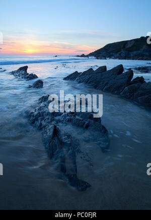 Sun setting over Dollar Cove at Gunwalloe in Cornwall Stock Photo