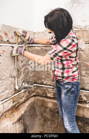 Clever woman repairing her bathroom sink pipe with  positive attitude. Using measuring tape ruler. Stock Photo