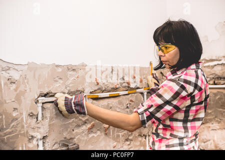 Clever woman repairing her bathroom sink pipe with  positive attitude. Using measuring tape ruler. Stock Photo