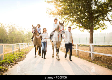 Cheerful young Chinese family riding horses Stock Photo