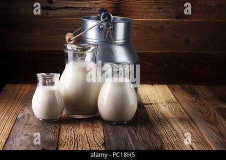 A jug of milk and glass of milk on a wooden table. Stock Photo