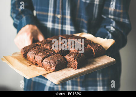 Vegan chocolate brownies on baking sheet. Young person holding plate with freshly baked vegan marijuana chocolate cakes Stock Photo