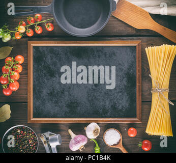 empty black frame and ingredients for pasta cooking on a wooden background, top view Stock Photo