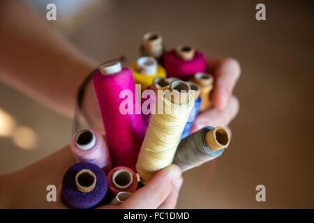 Many of colorful sewing thread bobbins in the gentle girls hands. Stock Photo