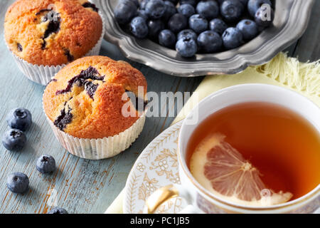 Close-up on blueberry muffin and cup of tea with lemon on gray rustic wooden table Stock Photo