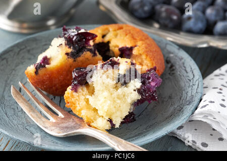 Close-up on broken blueberry muffin on gray rustic background with blueberries and paper napkin on rustic wooden table Stock Photo
