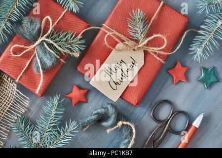 Rustic wooden background with fir branches and Christmas presents gift wrapped in red paper. Seasonal background shot from above. Flat lay, top view, 