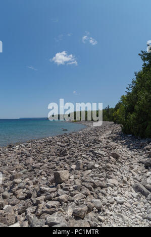 Bright clear aqua green water on Bruce Peninsula. Crystal clear water shows limestone rocks.  Cedar trees and conifers. Stock Photo