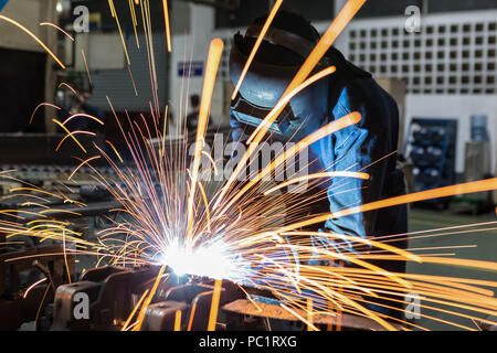 Worker is welding metal part with protective mask Stock Photo