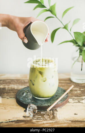 Iced matcha latte drink with milk pouring from pitcher Stock Photo