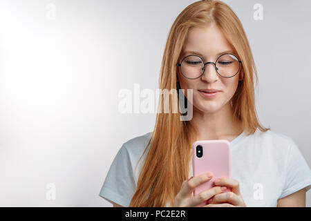 redhair model beaing impressed with great camera on the new smartphone.girl reads pleasant SMS. copy space Stock Photo