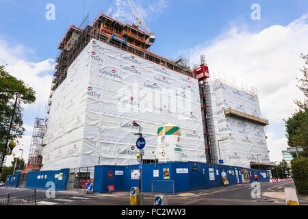 View of new residential apartment block under construction branded with the name of the developer, GallifordTry, on the scaffolding, Woking, Surrey Stock Photo