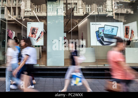 BELGRADE, SERBIA - JULY 11, 2018: Apple logo on Belgrade Apple Store  premium reseller twith people passing by in front. Apple Store is a chain of ret Stock Photo