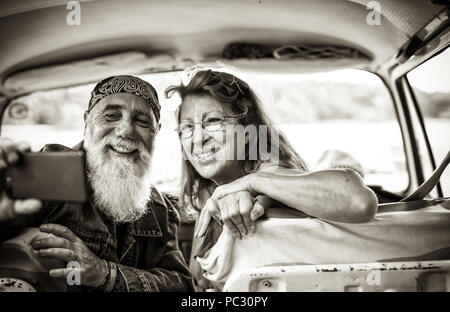  old hipster couple sitting in a van doing a selfie with a phone