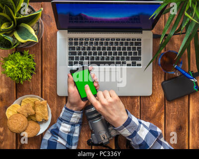 person scrolling news at smartphone with chroma key on a wooden table Stock Photo