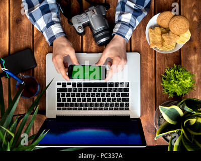 photographer working using phone and laptop on a wooden table Stock Photo